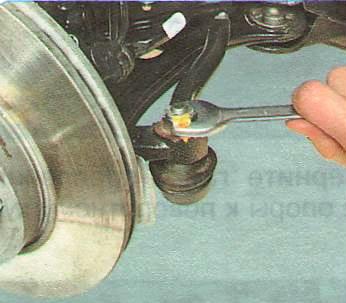 Отверните гайку крепления пальца шарнира наружного наконечника рулевой тяги.