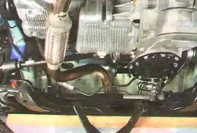 Слегка приспустите вниз поперечину передней подвески.