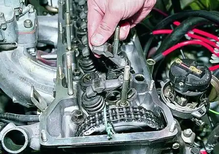 Приподнимаем рычаг клапана, освобождаем его от пружины. Снимаем рычаг