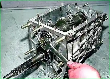 Нажав на муфты, включаем сразу две передачи и ключом «на 19» отворачиваем болт крепления переднего подшипника