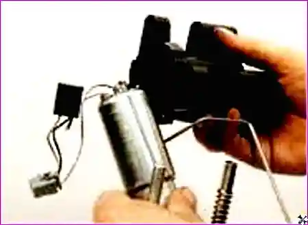 Палец нажимает на пластмассовый фиксатор крепления топливного насоса