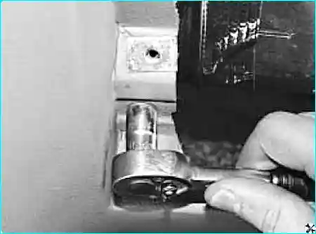 Отворачивание нижнего болта с левой стороны под вещевым ящиком